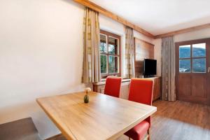 a dining room with a wooden table and red chairs at Gästehaus Panorama - Appartement 2 in Reit im Winkl