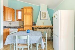 a kitchen with a table and a white refrigerator at Casa Erbì in Torre Dei Corsari