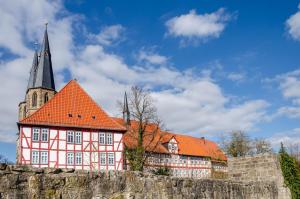 a pink building with a church behind a stone wall at Ferienwohnung am West-östlichen Tor in Ecklingerode