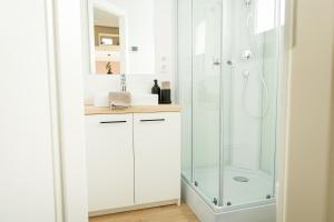 a white bathroom with a shower and a sink at Tiny Om Ferienhaus in Laichingen