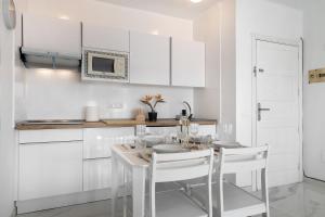 a kitchen with white cabinets and a table and chairs at Casa Fariones in Puerto del Carmen