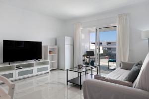 a white living room with a tv and a couch at Casa Fariones in Puerto del Carmen