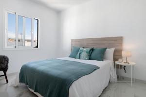 a white bedroom with a large bed with blue pillows at Casa Fariones in Puerto del Carmen +12 photos