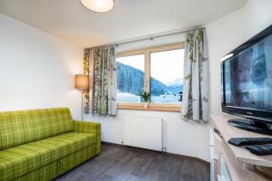 a living room with a green couch and a large window at Haus Sabrina Hexenkopf in See