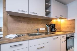 a kitchen with white cabinets and a sink at Haus Sabrina Hexenkopf in See