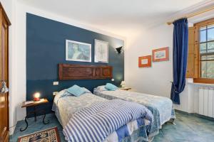 two beds in a room with blue walls at La Ripa - Appartamento Padronale in San Gimignano +24 photos