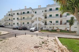 a large white building with cars parked in front of it at Algarvio ao Sol in Conceição