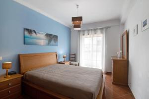 a bedroom with a bed and a blue wall at Algarvio ao Sol in Conceição