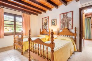 two beds in a bedroom with wooden ceilings at Villa Can Sol in Pollença +17 photos