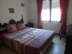 a bedroom with a bed and a window with red curtains at Villa Sylvie- Cerca Playa Riells- 4 in L'Escala