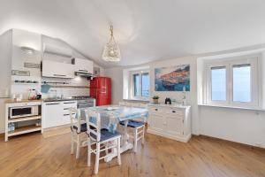 a kitchen with white cabinets and a table with chairs at Bedliving Nel Blu in Genoa