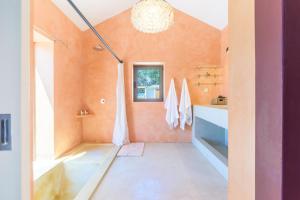 a bathroom with orange walls and a chandelier at Espaço Fataca - Sw Alentejano in São Teotónio +23 photos