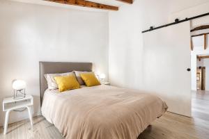 a white bedroom with a large bed with yellow pillows at Mirasol in Benitachell