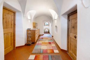 a hallway with a colorful tile floor and wooden doors at Bertollhof Apfelerlebnis in Silandro