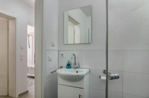 a white bathroom with a sink and a mirror at Fewo Köse in Uhldingen-Mühlhofen +16 photos