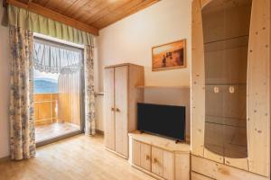 a living room with a tv and a large window at Residence Kronstein - Fewo 8 in Tesimo