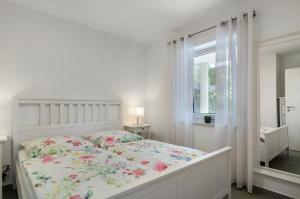 a white bedroom with a bed and a window at Fewo Köse in Uhldingen-Mühlhofen
