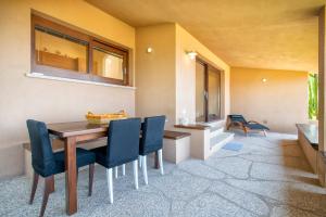 a dining room with a wooden table and blue chairs at Villa Amalthea - sea view-wellness in Costa Paradiso