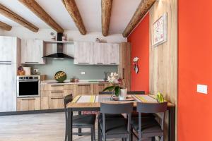 an orange kitchen with a wooden table and chairs at L'antica corte apt Angelina in Levico Terme