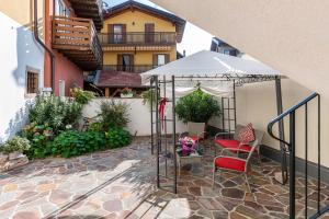 a patio with a red chair and an umbrella at L'antica corte apt Angelina in Levico Terme