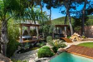 a garden with a swimming pool and a wooden deck at Casa Es Pins in Santa Eularia des Riu
