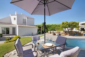 a patio with a table and chairs and an umbrella at Pine Lodge in Vilamoura