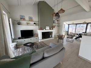 a living room with a couch and a tv at Villa des sablons, piscine chauffée in La Tranche-sur-Mer
