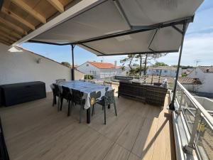 a patio with a table and chairs on a deck at Villa des sablons, piscine chauffée in La Tranche-sur-Mer