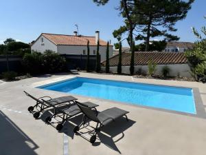 a pair of chairs and a swimming pool at Villa des sablons, piscine chauffée in La Tranche-sur-Mer