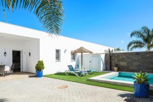 a white house with a swimming pool and a yard at Casa Orilla Sur A in El Palmar