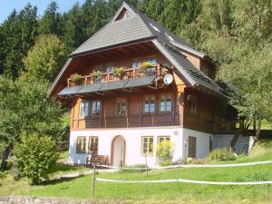 a large wooden house with a balcony on top of it at Am Neuhausbauernhof in Königsfeld im Schwarzwald