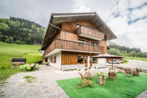 a large wooden house with a lawn and chairs at Coeur de Charmy Spa bien-être in Abondance