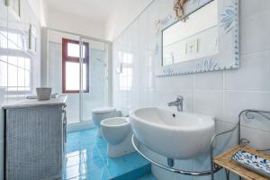 a white bathroom with a sink and two toilets at Casa Nicoleup in Porto Columbu - Perdʼe Sali +20 photos