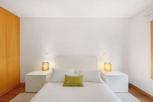 a white bedroom with a white bed and two night stands at Mary House in Matosinhos