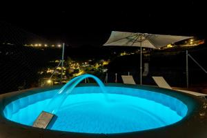 a blue swimming pool at night with an umbrella at Casa Rural La Escalerilla in Teror
