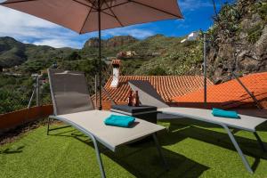 two chairs and an umbrella on top of a yard at Casa Rural La Escalerilla in Teror