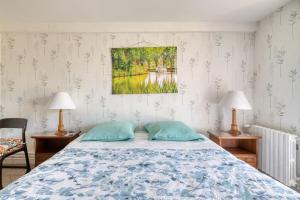 a bedroom with a bed and two lamps and a painting at Le Clos Rilda en Bounet in Villefranche-de-Lauragais