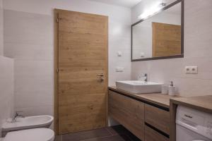 a bathroom with a sink and a toilet and a mirror at Lechnerhof Fane Alm in Valles +23 photos