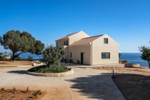 a white house with the ocean in the background at Joy Horizon in Skala