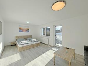 a white room with a bed and a table at Ferienwohnung Hochwangen in Ichenhausen
