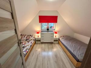 a attic bedroom with a bed and a dresser and a window at Gaj za Rzeką GNAP in Prusie