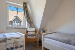 a bedroom with a bed and a chair and a window at Ferienhaus Düün Drööm in Ording