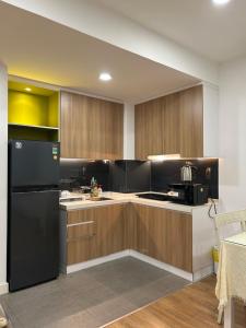 a kitchen with wooden cabinets and a black refrigerator at Căn hộ Republic Plaza gần Tân Sơn Nhất airport in Kon Rung (1)