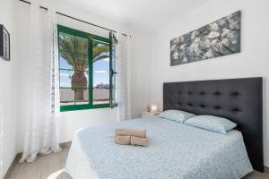 a bedroom with a bed with a blue comforter and a window at Casa Real in Playa Blanca