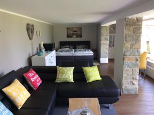 a living room with a black couch with colorful pillows at Ferienhaus Dell in Möhnesee
