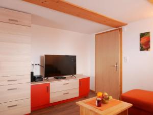 a living room with a television on a red cabinet at Haus Trötschler in Weilheim