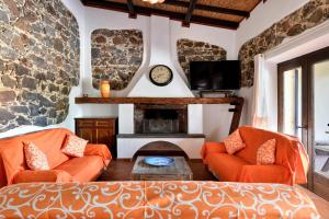 a living room with two orange couches and a fireplace at Casa sul lago private heated pool in Dorgali
