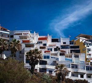 a white apartment building with palm trees in the foreground at Olas del Atlántico in Tacoronte