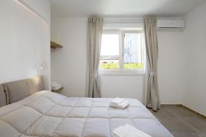 a white bedroom with a large bed and a window at Appartamenti Dama 2 in Bardolino