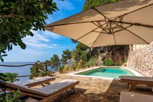 a pool with two chairs and an umbrella at Es Racó d'Alconàsser in Sóller